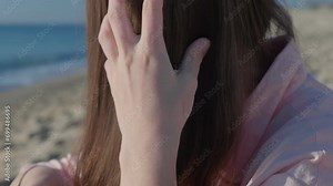Young woman carefully combs each strand of hair tangled by wind