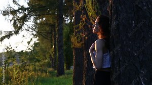 Beautiful happy woman enjoing good warm autumn weather on sunset background in fashion clothes near the tree in the park