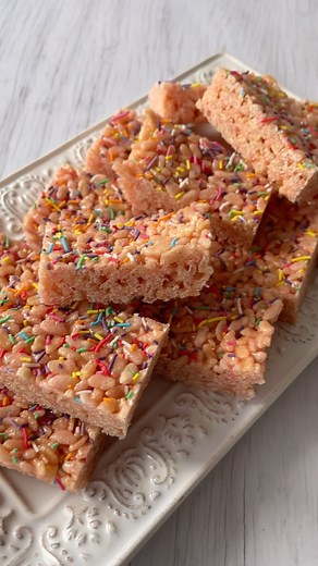💕 Marshmallow Rice Bubble Slice - Homemade LCMs 💕 Ingredients: * 80g butter * 180g marshmallows * 1 tsp vanilla essence * 4 cups rice bubbles * Sprinkles Method: 1. Line a 17 x 27cm baking tray with baking paper and set aside. 2. Place the butter in a large saucepan over a low heat and melt. 3. Add the marshmallows to the melted butter. Mix until completely melted and combined. 4. Add the vanilla, stir to combine then remove from the heat. 5. Add the rice bubbles to the saucepan and work quick