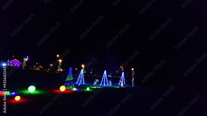 A drive through a Christmas light display at night, featuring twinkling lights and decorated trees. . High quality 4k footage