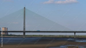Panning shot of Mersey Gateway Bridge from Runcorn town side to Widnes, power station and it's round cooling towers seen in the background.