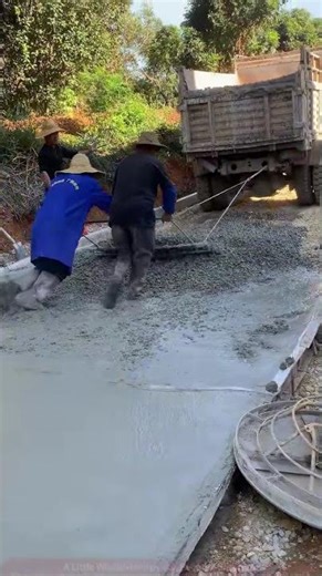 Rural Road Paving: Workers Leveling Concrete with Simple Tools