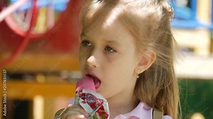 Little girl eating ice cream on a hot summer day at playground in park.