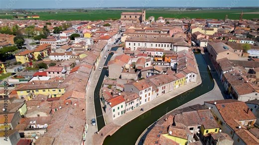 Comacchio aerial 4k high view over canals and red roofs in Italy. Panoramic skyline of Little Venice in Emilia Romagna hidden gem. Scenic water channels and traditional architecture scenery