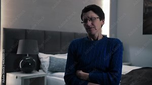 Senior woman has stomach ache while sitting at the couch.Adult lady has stomach hurts at home.Woman feels badly in bedroom.