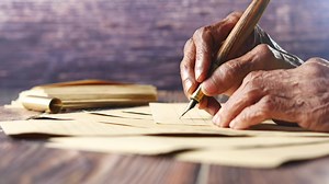 an old man writing on paper with a pen