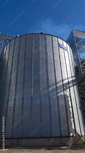 Exterior of grain elevators on field. Large granary of a modern industrial plant for agriculture. Industrial complex for storage crop. Vertical video