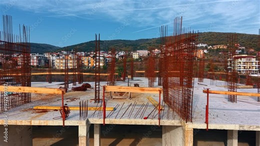 Reinforced concrete columns with vertical steel rebar rods. Close-up view of concrete columns with protruding steel reinforcement bars on a building floor.