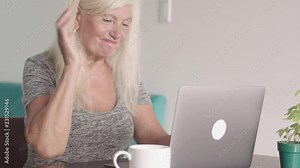 Close up shot of retired old woman ( grandmother ) using laptop at home in the living room. Elderly woman doing shopping online and pay bill by credit bank card using her modern PC. Online purchase