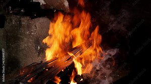 Burning fire in furnace at forge, workshop. Blacksmith equipment concept. Blacksmith's open forge, bright flame and smoke, heating up metal ingot for forging.