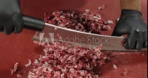 Chef hands chop the meat with a big knife. Top view. Preparation of minced meat for cutlets, meatballs, chops, burgers. Slow motion