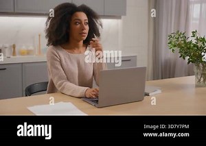 Pensive thinking African American woman using computer indoors freelancer girl distant working from home browsing laptop in kitchen business female pondering solution idea typing cyberspace e-learning