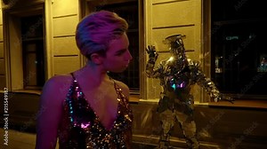 Young girl with stylish hairstyle walking at night. Actor in disco ball costume dancing under street lamps. Night city life.