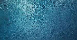 Aerial: top down view of blue ocean surface, turquoise sea water background