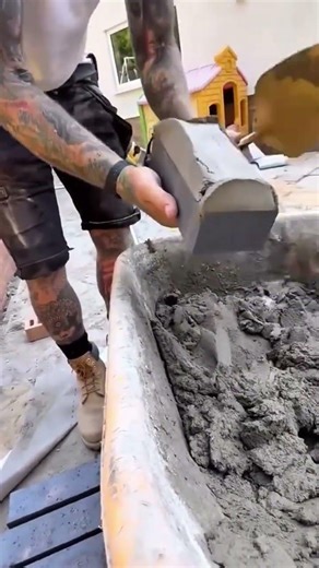 scooping wet mortar onto a grey brick and then placing it carefully on brick wall using string line