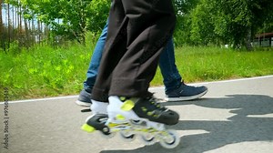 Positive caring father helping cute teenage daughter to ride roller skates in public park. Affectionate dad teaching little girl rollerblading outdoors during weekend.