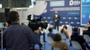 A videographer is filming the speakers in the conference room.