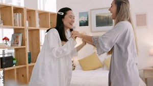 Celebration, love and friends on her wedding morning dancing, hugging and bonding in a bedroom. Happy bride and bridesmaid celebrating the day of the marriage ceremony while getting ready together.