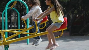 Sweet children playing on a teeter totter in a playground