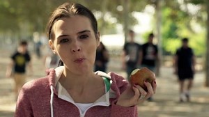 Portrait of happy woman eating apple in park, slow motion shoot at 120fps