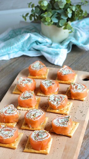 Receta de canapés de salmón DE SALMÓN: INGREDIENTES: 200 g de salmón ahumado en lonchas 175 g de queso crema 4 pepinillos 20 g de alcaparras 1 pizca de eneldo 12 tostadas cuadradas ELABORACIÓN: 1. Extiende un film de cocina grande y coloca encima las lonchas de salmón ahumado en forma de cuadrado, es importante que no quede ningún hueco entre ellas para que no se salga el relleno. 2. Mezcla el queso con los encurtidos muy picaditos y repártelo por encima del salmón dejando un trozo al final sin