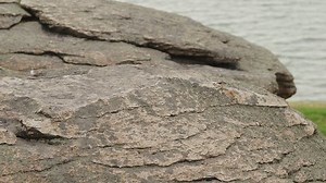 Man climbing barefoot on a rock with yoga mat to do exercises