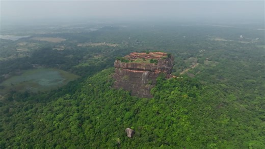 Sri Lanka landscape view of Sigiriya Rock Fortress across a lotus lake and green wetland under bright sky | Premium Stock Video Footage