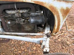 Hand crank starting a grey fergy tractor.