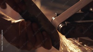 Man sharpening knife with sparks. Work on a sharpening machine.