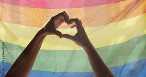 Love sign. Celebration Event Symbol Of LGBT. Love Equal. LGBT rights. human relationships. Gay and lesbian pride lgbt flag. Supporting hands make heart sign and wave in front of a rainbow flag flying.