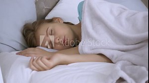 beautiful girl sleeping in bed open eyes looking at the camera happy smiling. young woman lying on pillows in bedroom Stock Video