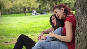 Two beautiful sexy lesbian women resting on a tree