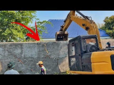 Operation excavator destroying concrete fence wall, length 20 metres