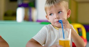 Cute children drinking soda or soft drink with straw in a fast food restaurant
