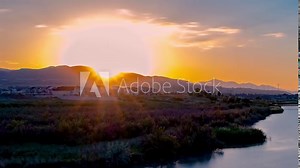 Zooming out and panning time lapse to reveal a beautiful river and ladscape at sunset as the scene transitions to night