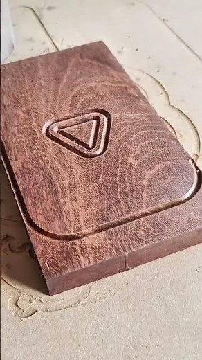 CNC machine is carving triangle logo and line pattern on brown wood surface