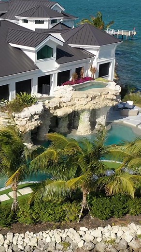 Elevated spa with an infinity edge that spills over a natural coral waterfall into the main pool below. The colors of this pool reflect the warm coral rocks and the vibrant hues of the Atlantic Ocean and the Gulf of Mexico. #insanepools #lucaslagoons #poolbuilder #poolside #poolparty #lazyriver #backyard #luxurylifestyle #luxuryhomes #luxurypool #floridakeys | Lucas Lagoons