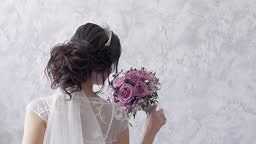 brunette bride with tiara and white veil on hairdress holds purple...