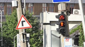 Traffic light is broken and yellow light doesn't work. Works red and switches to green. Road sign going straight. Old houses on background