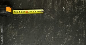 Construction tape measure on a textural black background. Looped 4K stop motion animation with space for text