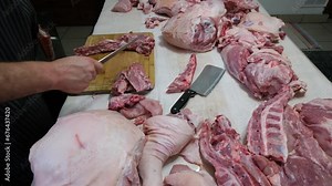 Time lapse while cutting and separating or trimming pork bones from meat from freshly butchered and portioned hog.