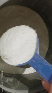 Vertical video. Measuring a portion of powder, shaking off the excess to get the precise amount. Slow motion.