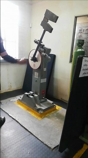 SWINGING AND DROPPING CHARPY IMPACT MACHINE HEAVY HAMMER FOR IMPACT TESTING PURPOSES AT ROOM TEMP.