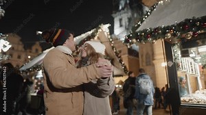 Beautiful scene of friends couple dancing slowly in a middle of christmas fare in european town. Touching moment during holiday season celebration.