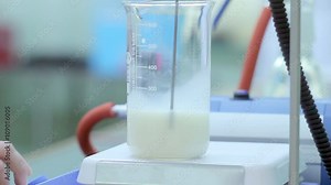 Analysis of milk. Laboratory scientist put measuring cup with liquid on laboratory equipment. Chemical laboratory. Testing milk on fat percentage. Research milk quality in chemistry laboratory