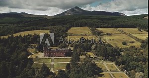 Scotland landscape aerial shot: mountains, ancient Brodick Castle with Goatfell mount. Epic scenery of Scottish landmarks. Wonderful forests and valleys at summer day. Footage wide view in 4k, UHD