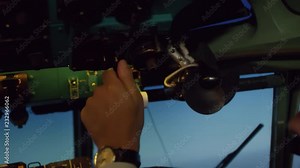 Handheld shot of male pilot in headset controlling plane in cockpit: he is using yoke and operating switches on overhead instrument Panel Stock Video