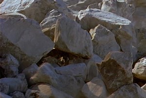 Boulders and smaller rocks roll and slide down a hill during a landslide.