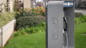 Retro coin-operated payphone station for emergency call on street, California USA. Public analog pay phone booth. Outdated technology for connection and telecommunication service. Cell handset on box.