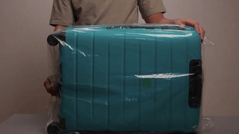 clip-3997785035-luggage-wrapping-process-worker-securing-suitcase-protective